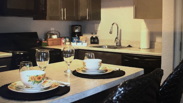 A modern kitchen with dark cabinetry, a microwave, and a coffee maker on the counter.