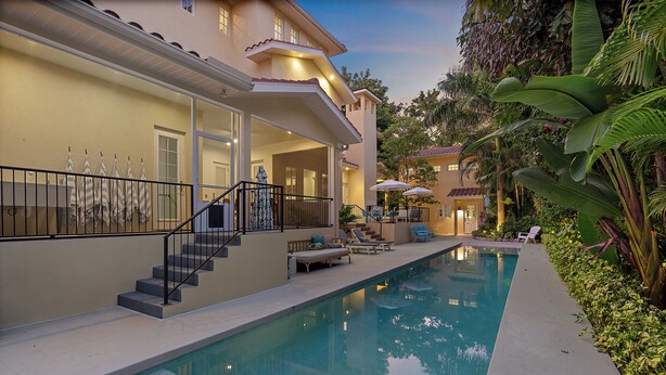 A poolside area with a clear pool, outdoor seating, and a staircase leading to a covered area. - Sapphire Shores | Luxury Pool, 2 Fireplaces, Game Room + 2 Bars! (Sarasota)