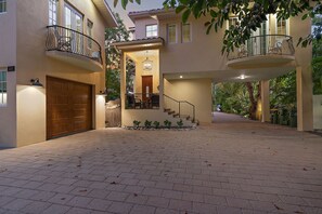 A two-story house with a covered front porch, a wooden garage door, and a staircase leading to the second floor.