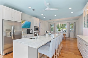 A modern kitchen with a central island, stainless steel appliances, and a large window providing natural light.