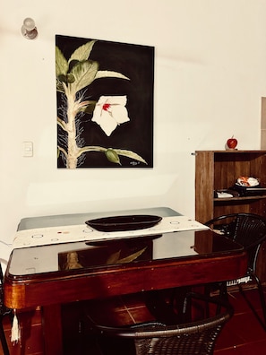 Un comedor con una mesa, sillas, un cuadro en la pared y un mueble de madera con una manzana encima.