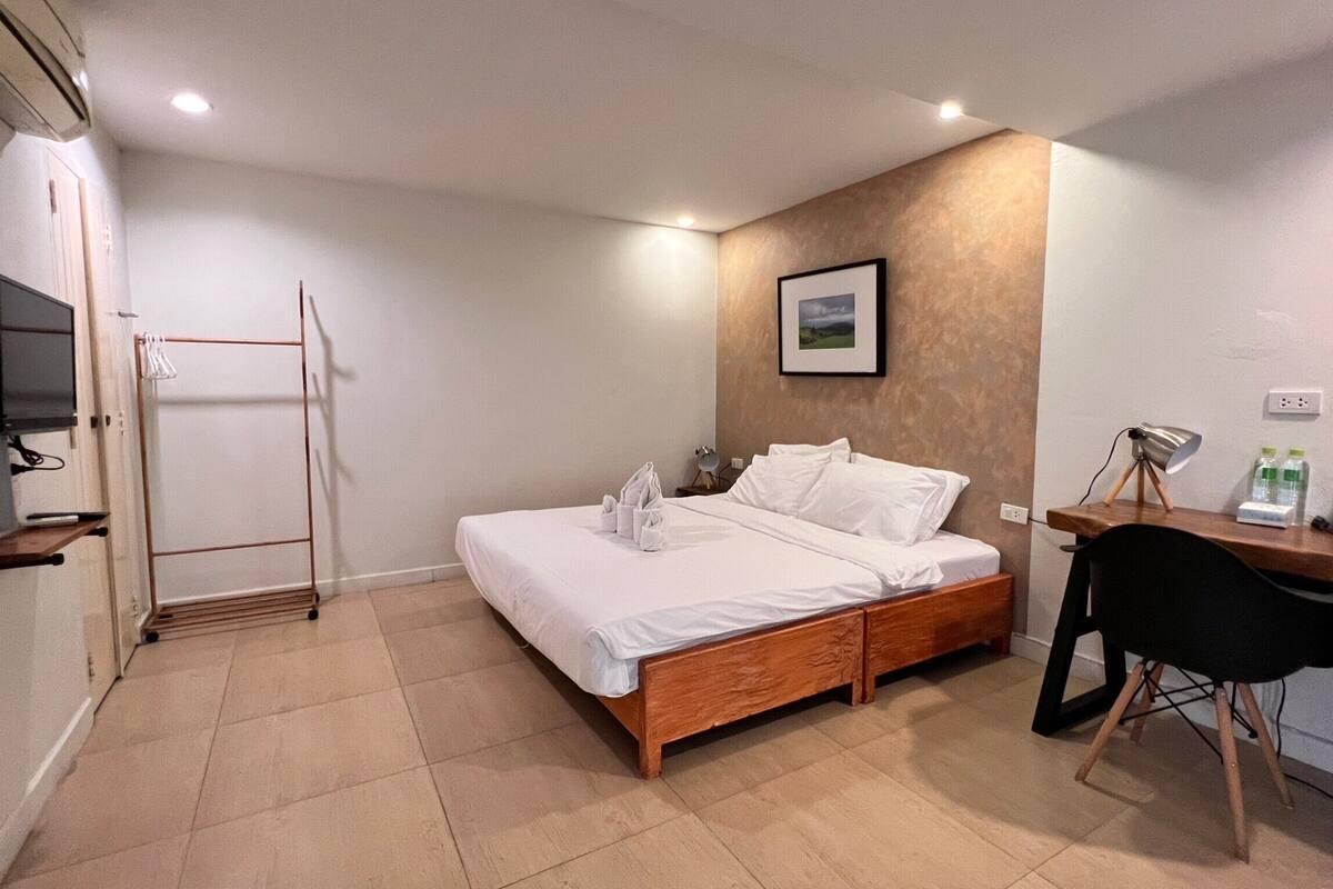 Ein Schlafzimmer mit einem Bett, einem Schreibtisch, einem Stuhl, einem Fernseher und einem Handtuchhalter.