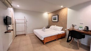 A bedroom with a bed, a desk, a chair, a TV, and a towel rack. - UDEE Cozy Hotel (Chiang Mai)