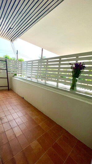 A balcony with a white railing, a tiled floor, and a vase with purple flowers. - UDEE Cozy Hotel (Chiang Mai)