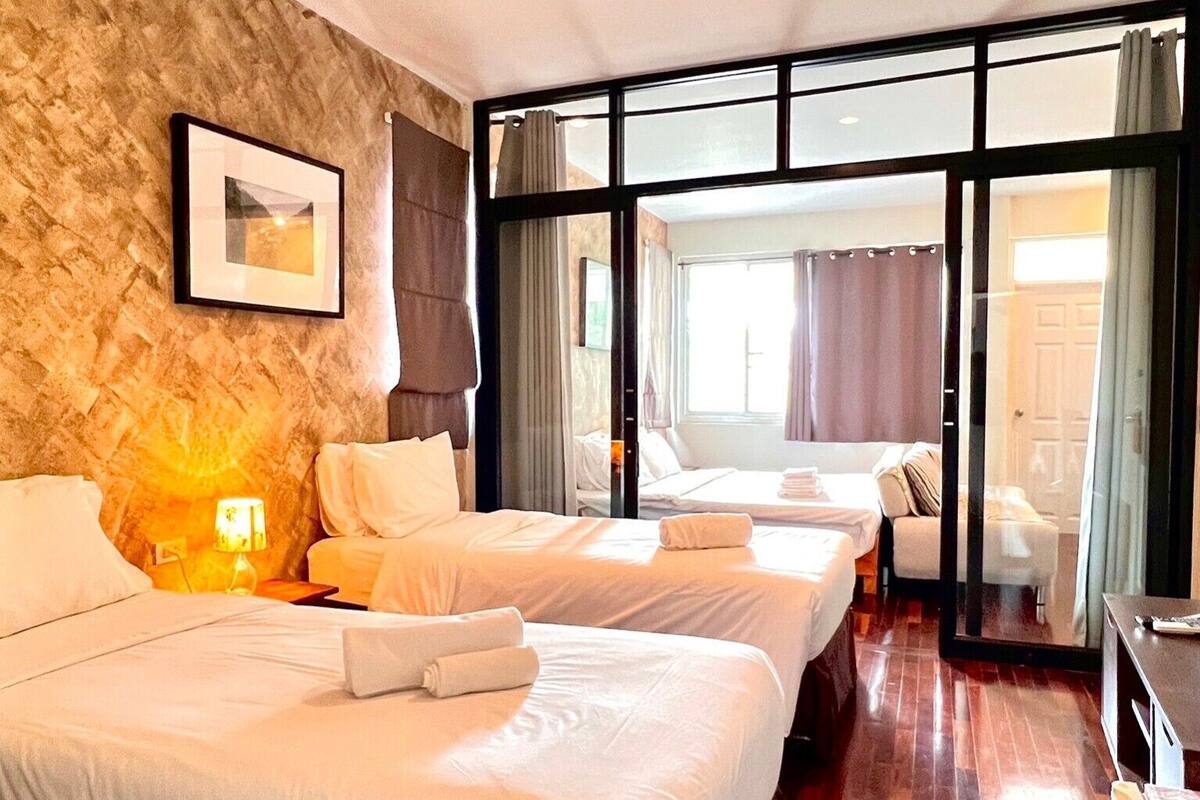 Ein Hotelzimmer mit zwei Betten, einer Steinwand, einem großen Fenster und einem Holzboden.