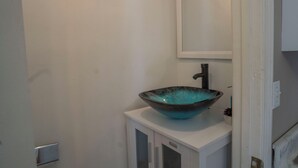 A bathroom with a white cabinet, a blue glass bowl sink, and a mirror above it. - Nice and Cousy guest suite (Roswell)
