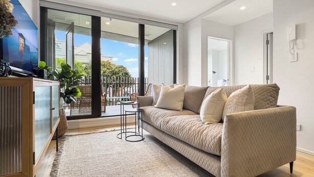 A modern living room with a beige sofa, a small side table, and a cabinet. - Creative and Carefree Living (Auckland)