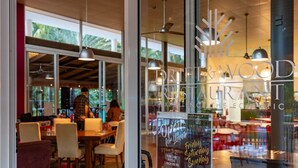 Ein Restaurant mit modernem Interieur, großen Fenstern und hängenden Pendelleuchten.