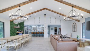Un vaste espace de vie comprenant une table à manger en bois, des sièges confortables et une cuisine située à l’arrière-plan.