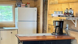 A kitchen with a wooden island, two stools, a refrigerator, and a coffee maker. - Classic Seaman's Lodge - directly across from the Quarterdeck (Pet Friendly!) (Summerville Center)