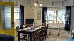 A cozy dining area with a wooden table, chairs, and a dog resting on a couch. - Classic Seaman's Lodge - directly across from the Quarterdeck (Pet Friendly!) (Summerville Center)