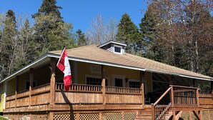 A lodge with a wooden deck, a flag, and a sign indicating it's a lodge. - Classic Seaman's Lodge - directly across from the Quarterdeck (Pet Friendly!) (Summerville Center)