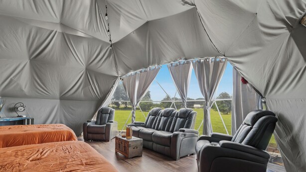 Eine Zelthütte mit zwei Betten, einem Sofa, einem Sessel und einem kleinen Tisch.
