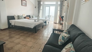 Et værelse med to senge, en sofa og en balkon.