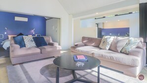 Un soggiorno moderno con due divani, un tavolino e una zona cucina visibile attraverso una porta aperta.