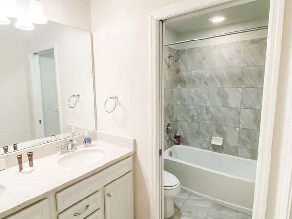 A bathroom with a double sink vanity, a mirror, a shower with a glass door, and a toilet.