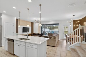 A modern kitchen with a central island, white cabinetry, and pendant lighting.