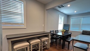A modern kitchen with a bar area, wooden flooring, and built-in seating. - Cheerful 2 Home (Riviera Beach)