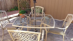 A round glass-top table with four chairs, each with a woven seat and backrest. - Your Home in Monterey, CA (Monterey)