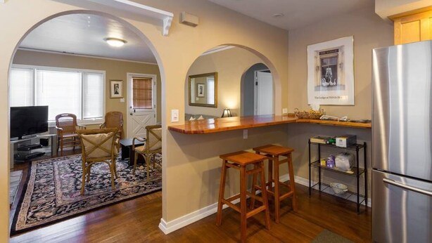 A kitchen with wooden bar stools, a stainless steel refrigerator, and a wooden counter. - Your Home in Monterey, CA (Monterey)