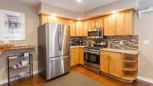 A modern kitchen with stainless steel appliances, wooden cabinets, and a tiled backsplash. - Your Home in Monterey, CA (Monterey)