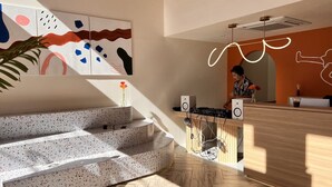 Un área de recepción moderna con un mostrador de madera, dos altavoces y una persona trabajando detrás.