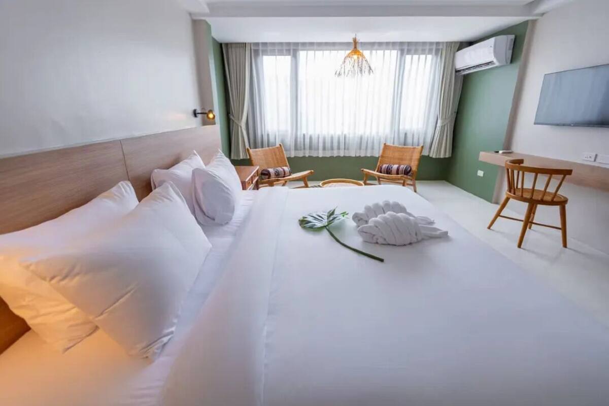 A hotel room with a large bed, two chairs, a desk, and a TV.