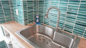 Ein Spülbecken aus Edelstahl mit einem modernen Wasserhahn, einer Seifenspender und einem Gitterabfluss.
