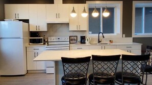 A modern kitchen with white cabinets, a central island, and pendant lighting.