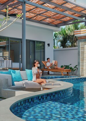Un espace piscine extérieur moderne, doté d’une bordure incurvée, d’un coin salon abrité et d’une porte vitrée donnant accès à une pièce.
