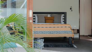 A modern bedroom with a bed, bedside table, and a view of a pool area.