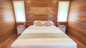 Une chambre avec un grand lit, des lambris en bois sur les murs, deux tables de chevet avec des lampes et un élément décoratif mural au-dessus du lit.