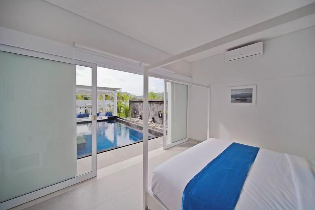 A modern hotel room with a large sliding glass door leading to a pool area.