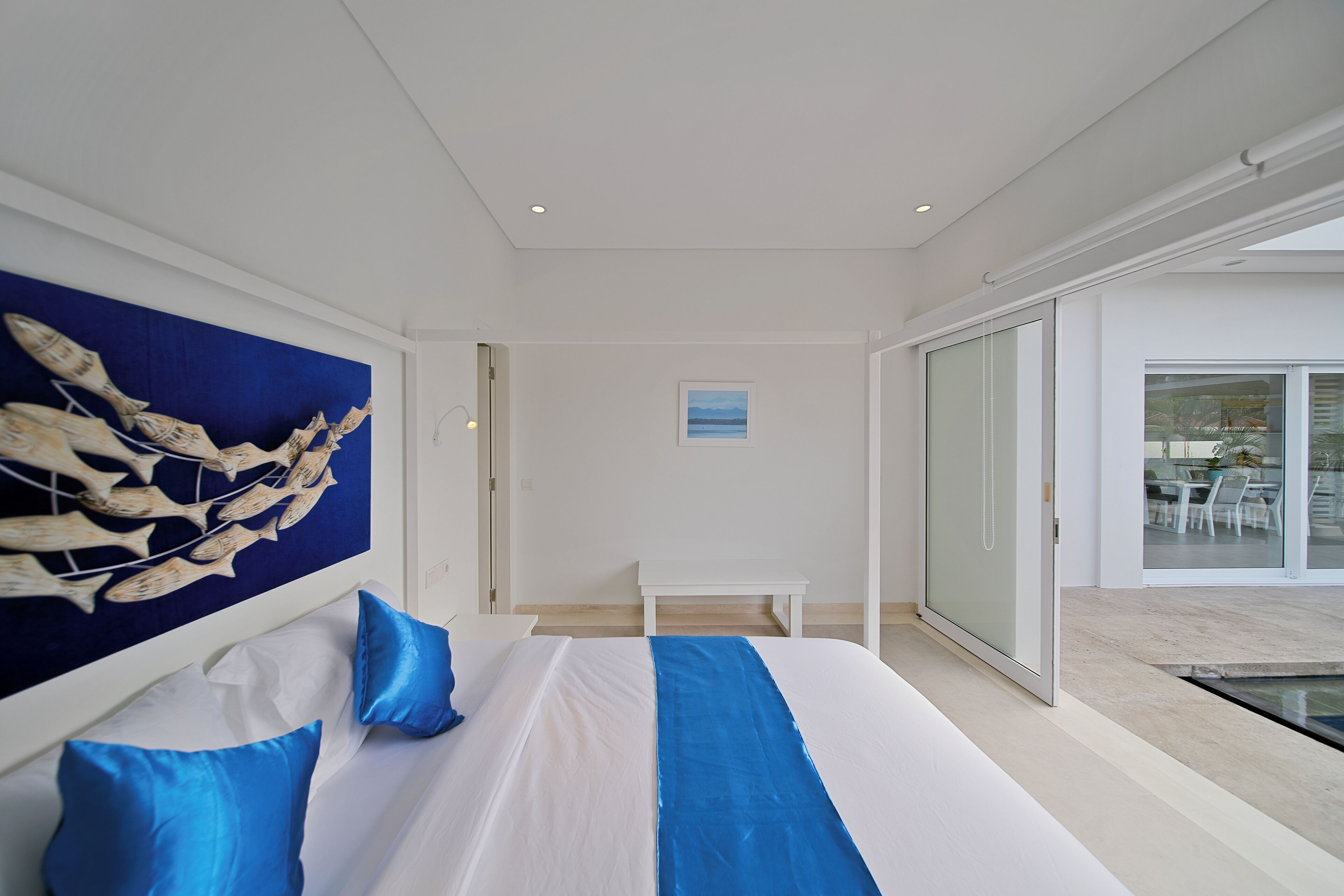 Habitación de hotel moderna con una cama grande, vistas al exterior y un ventanal que da a un balcón.