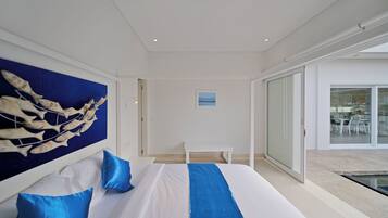 Habitación de hotel moderna con una cama grande, vistas al exterior y un ventanal que da a un balcón.