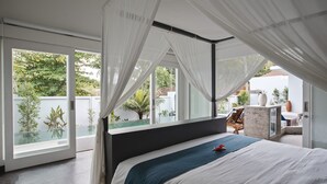 A bedroom with a large bed, white curtains, and a view of a garden and pool.