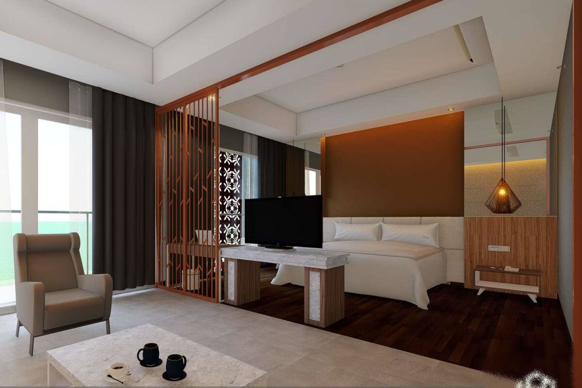 A modern hotel room with a large window, a sofa, a TV, and a wooden partition.