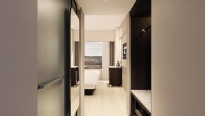 Een hotelkamer met een bed, een bureau, uitzicht op de stad en een donkerhouten garderobe.