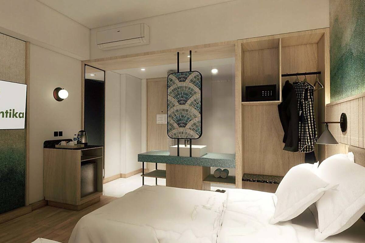 A hotel room with a bed, a desk, a mirror, and a sign for Hotel Santika.