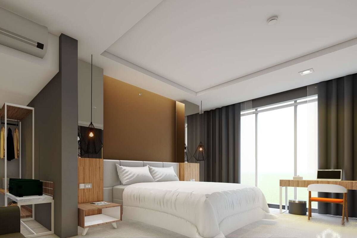 A modern hotel room with a large bed, a desk, and a wardrobe.