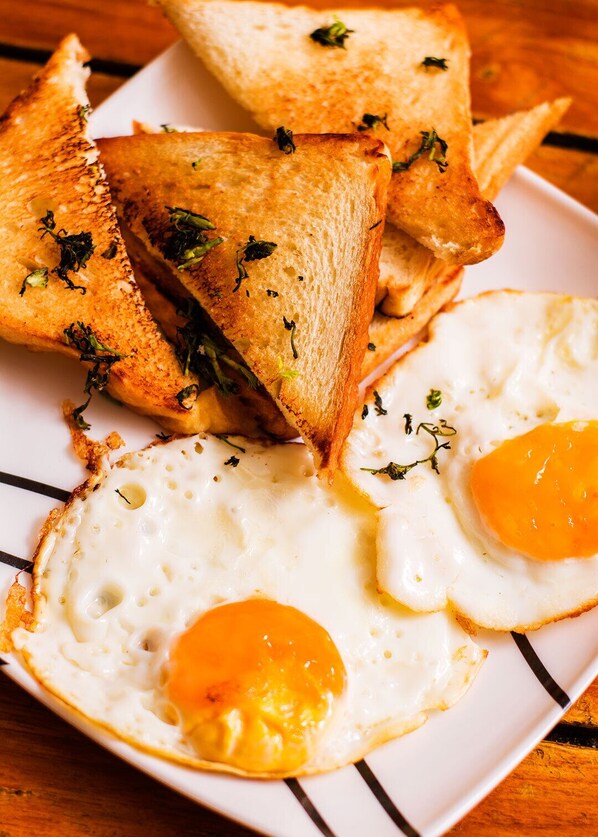 Toasted bread slices and fried eggs on a plate. - HOSTAL LA BOQUILLA (Cartagena)