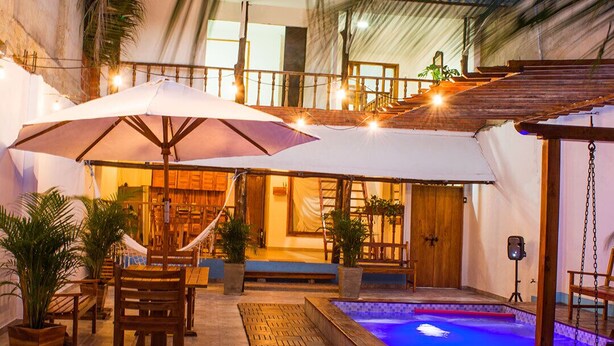 An outdoor patio area with a pool, wooden furniture, and umbrellas. - HOSTAL LA BOQUILLA (Cartagena)