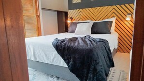 A neatly made bed with a white duvet and a dark blanket, a wooden headboard with a chevron pattern, and two wall-mounted lights. - HOSTAL LA BOQUILLA (Cartagena)