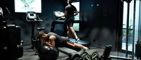 A gym with exercise equipment, a treadmill, and a large window.