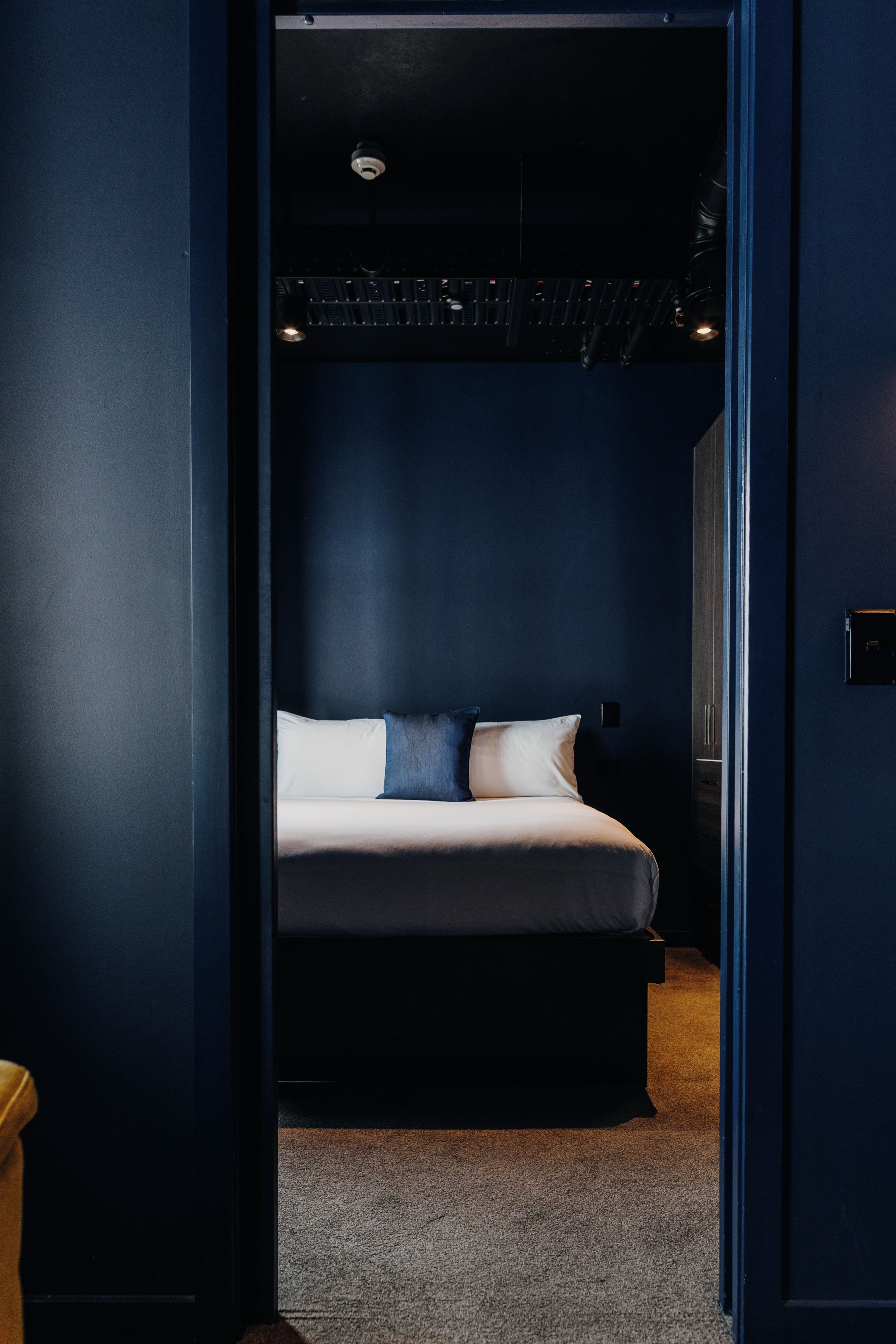 A bedroom with a bed, a nightstand, and a dark ceiling.