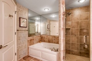 A bathroom with a bathtub, a shower, and a large mirror.