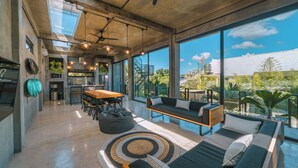 A spacious living area with a sofa, a dining table, and a kitchen in the background. - Villa Konkrete - Tropical 3BR (Kerobokan)