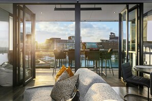 Relax in this spacious living area with a sofa, dining table, and panoramic city and water views.