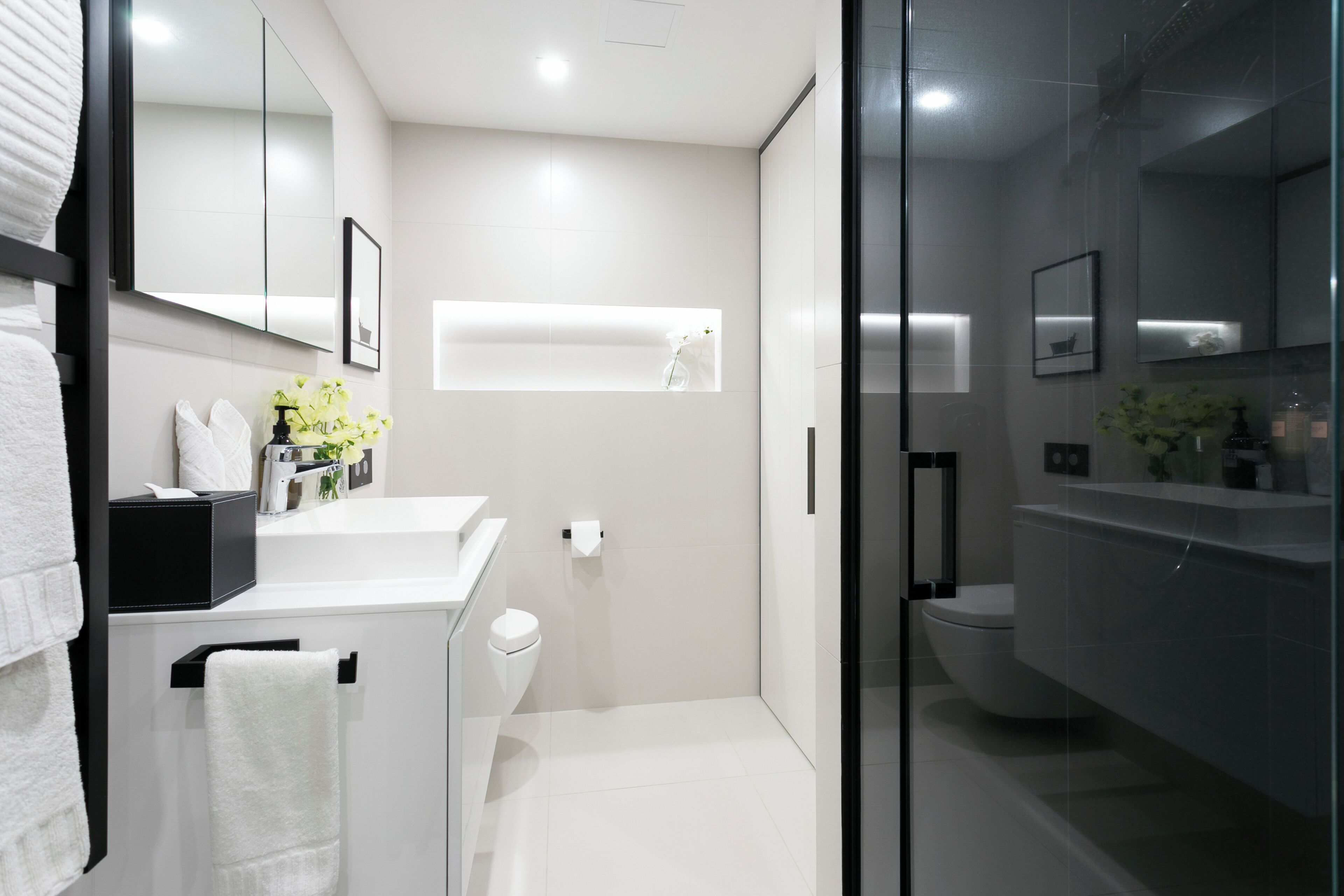 A modern bathroom with a glass shower enclosure, a white sink, and a toilet.