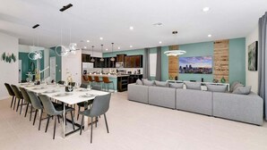 Ein moderner Wohnraum mit Essbereich, Küche und einem großen grauen Sofa.